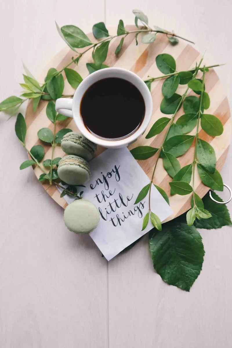 Copy Corner Blog flat lay photography of leaves with cup of coffee and three macarons on chopping board